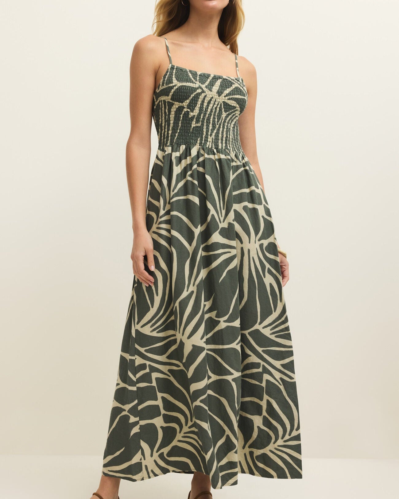 Woman wearing a green and beige patterned dress on a white background