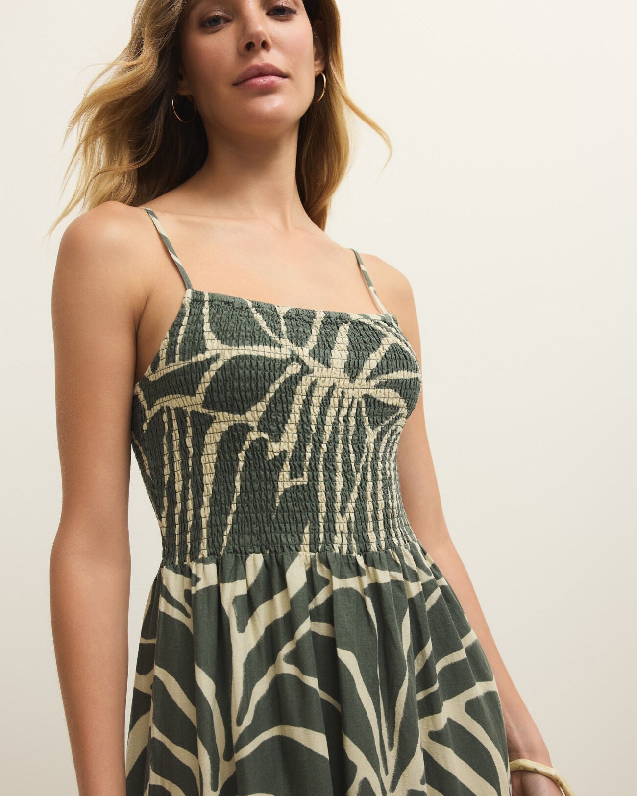 Woman wearing a green and beige patterned dress against a plain background