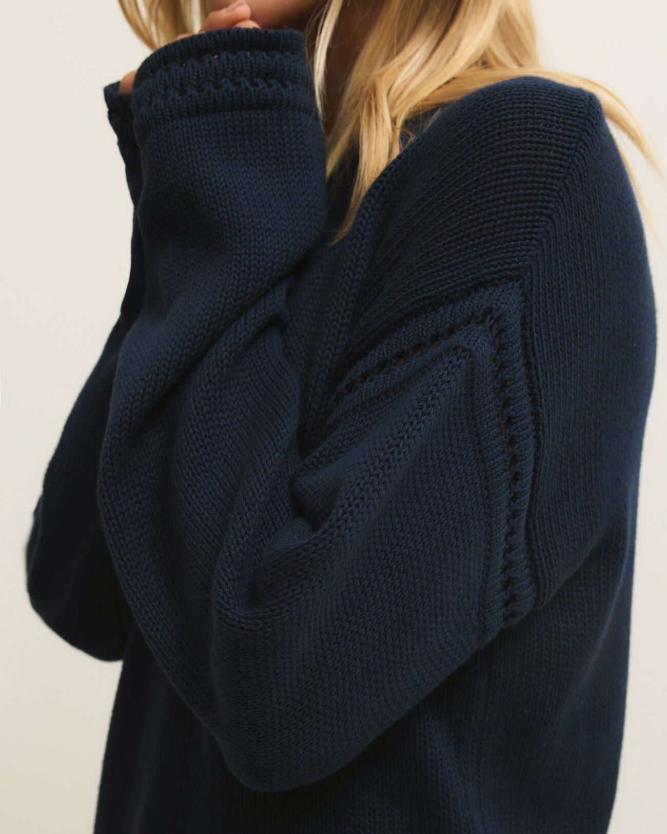 Navy blue sweater worn by a person on a beige background