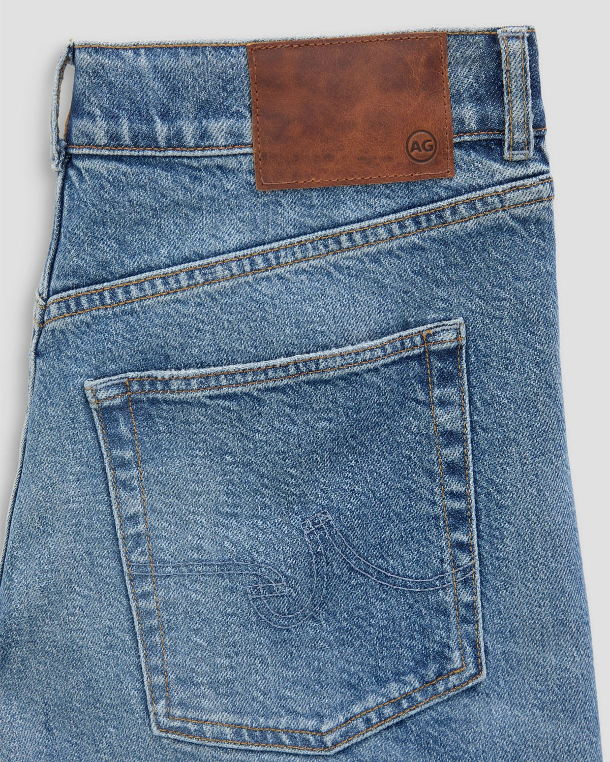 Blue jeans with a brown leather patch on a white background