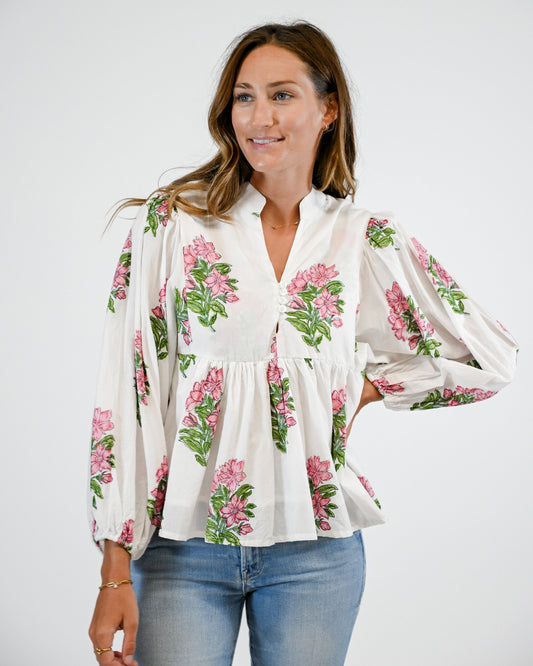 Woman wearing a white blouse with floral patterns and blue jeans on a white background