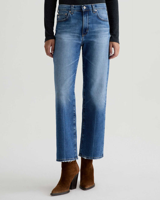Person wearing blue jeans and brown boots on a white background