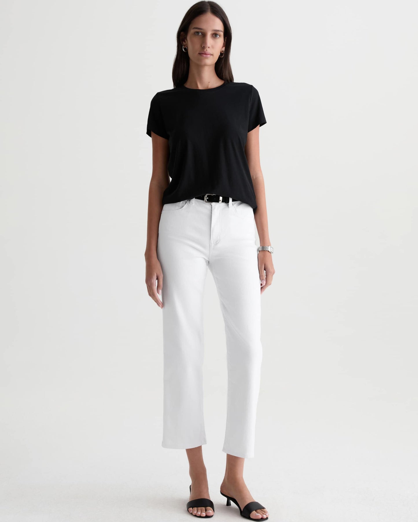 Woman wearing a black t-shirt and white pants on a white background