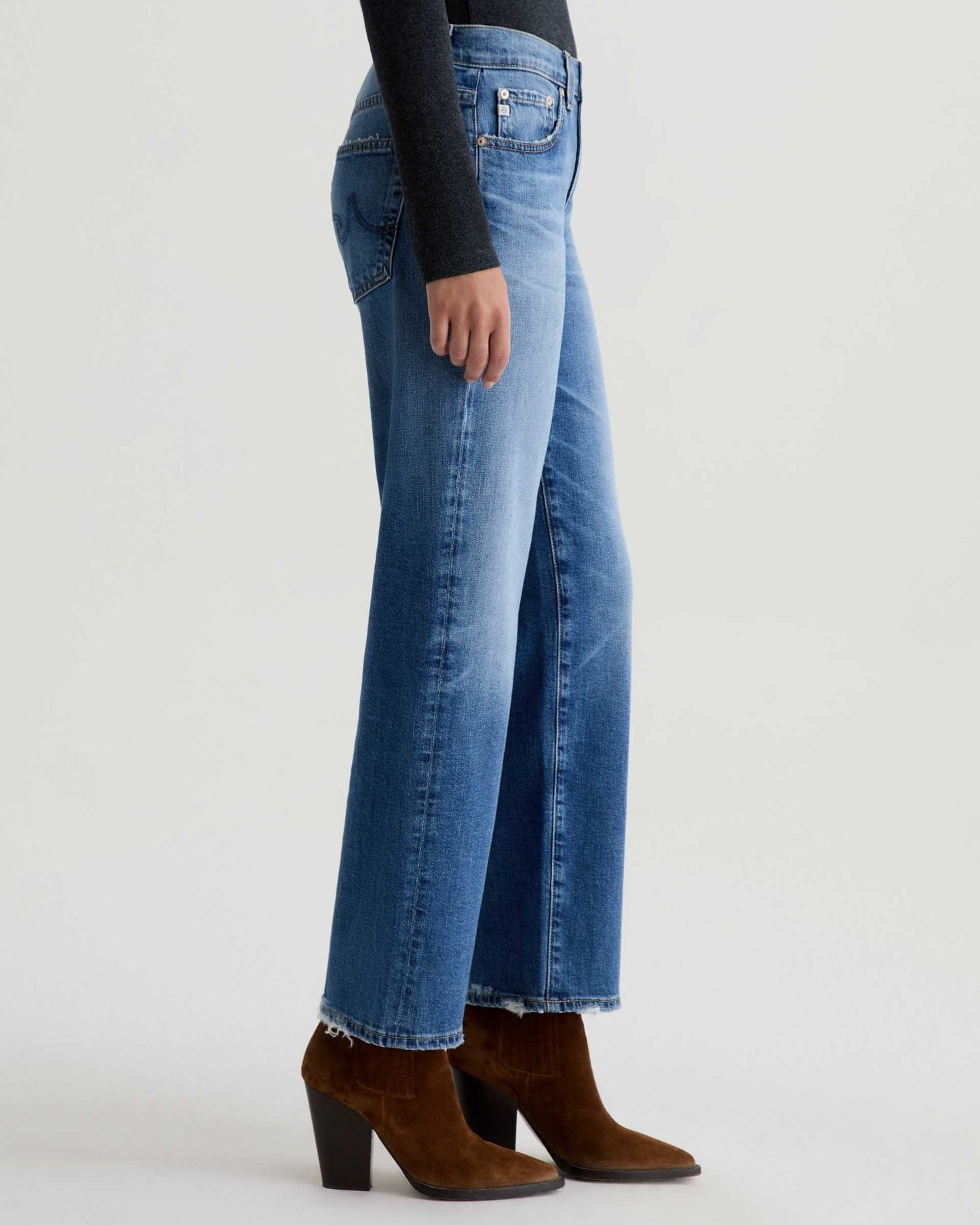 Person wearing blue jeans and brown boots on a white background