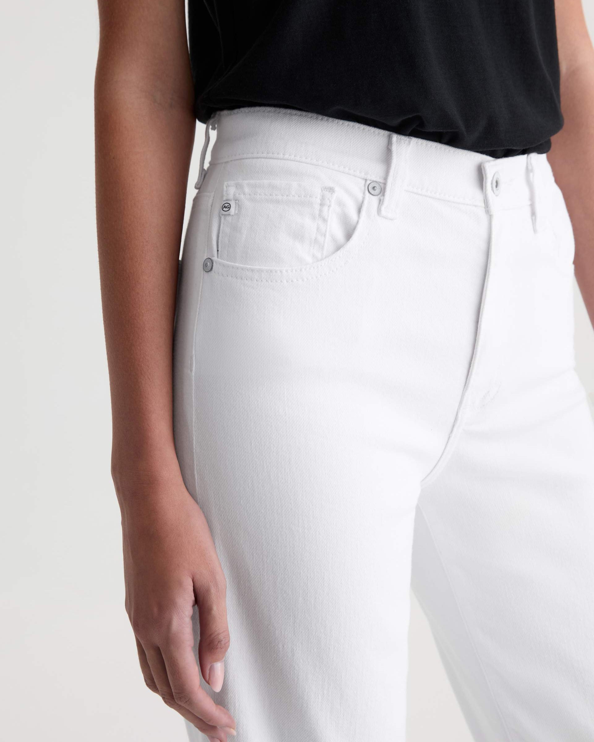 Person wearing white jeans and a black top on a plain background