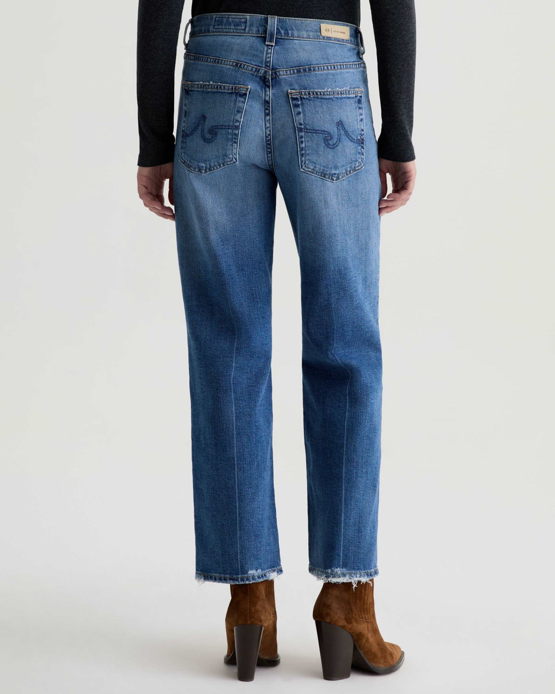 Person wearing blue jeans with a plain background