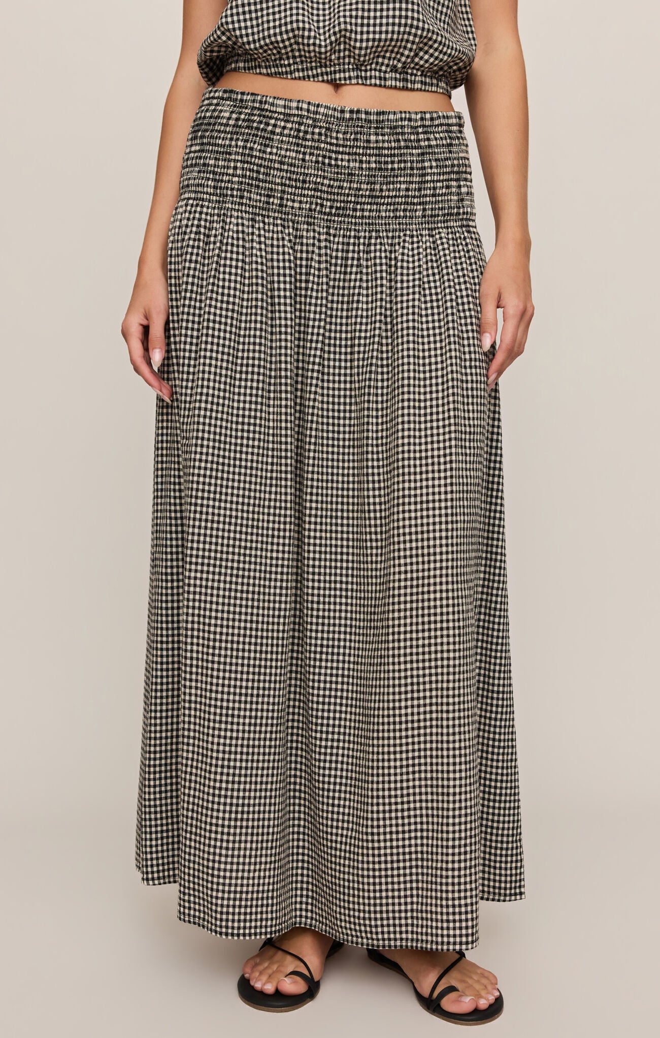 Person wearing a black and white checkered skirt on a beige background