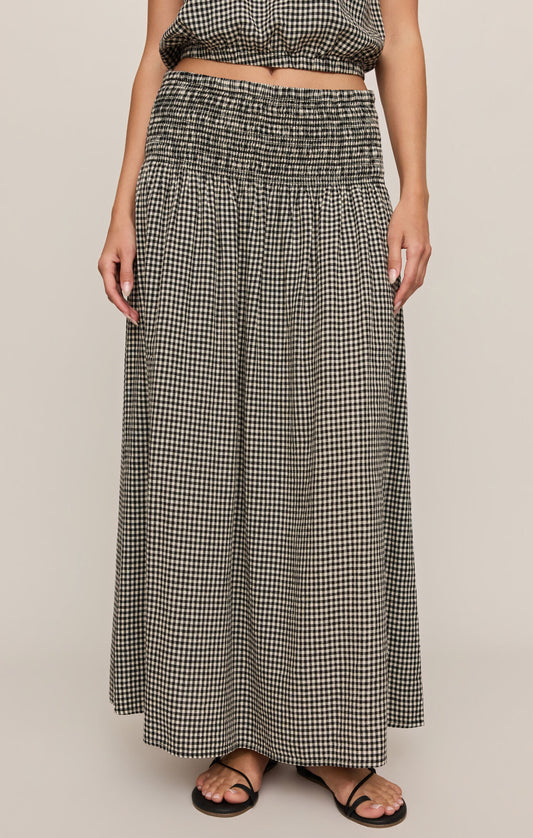 Person wearing a black and white checkered skirt on a beige background