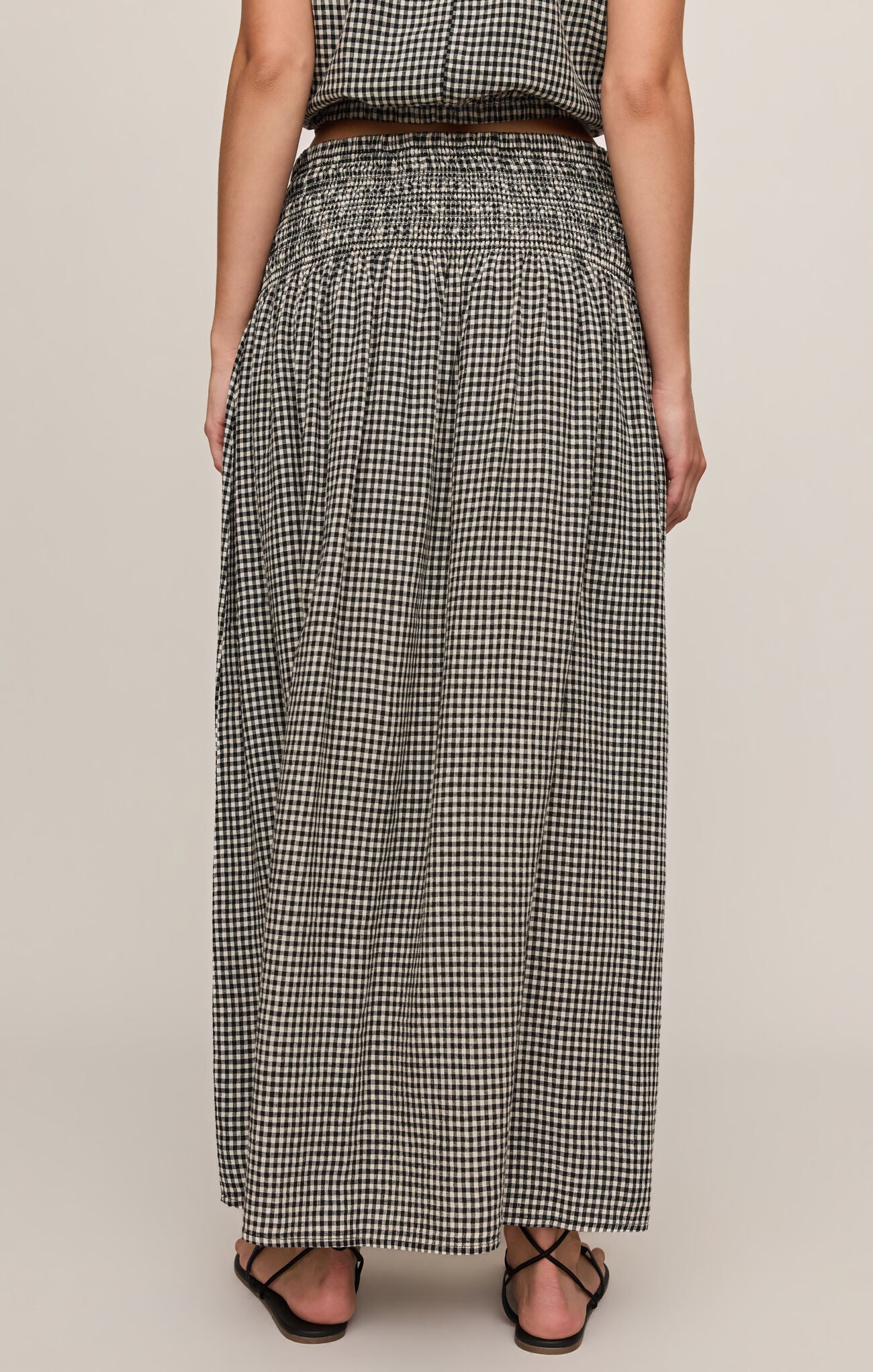 Person wearing a black and white checkered skirt on a beige background