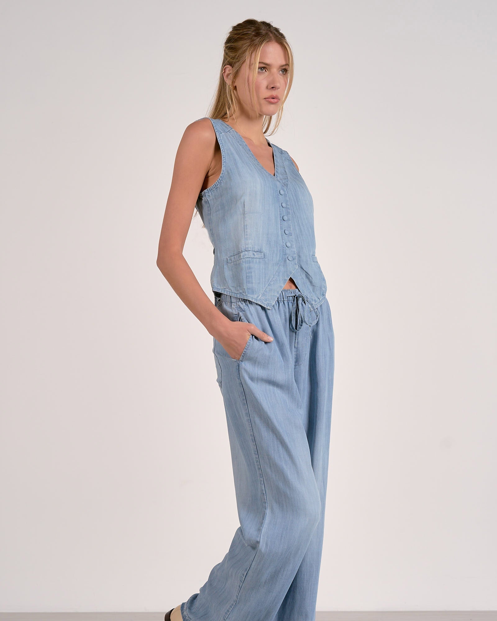 Woman wearing a light blue denim jumpsuit on a white background