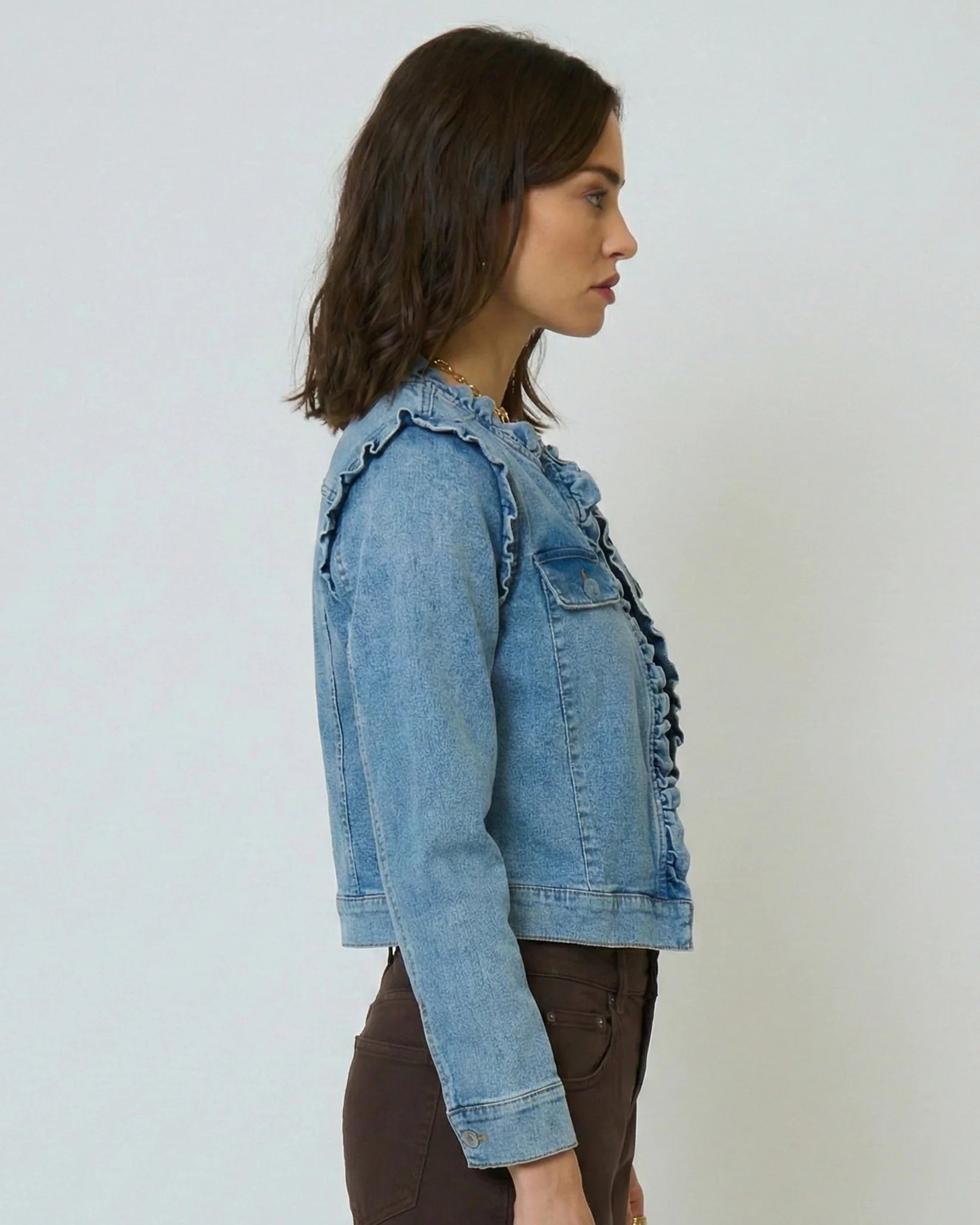 Woman wearing a light blue denim jacket against a plain background
