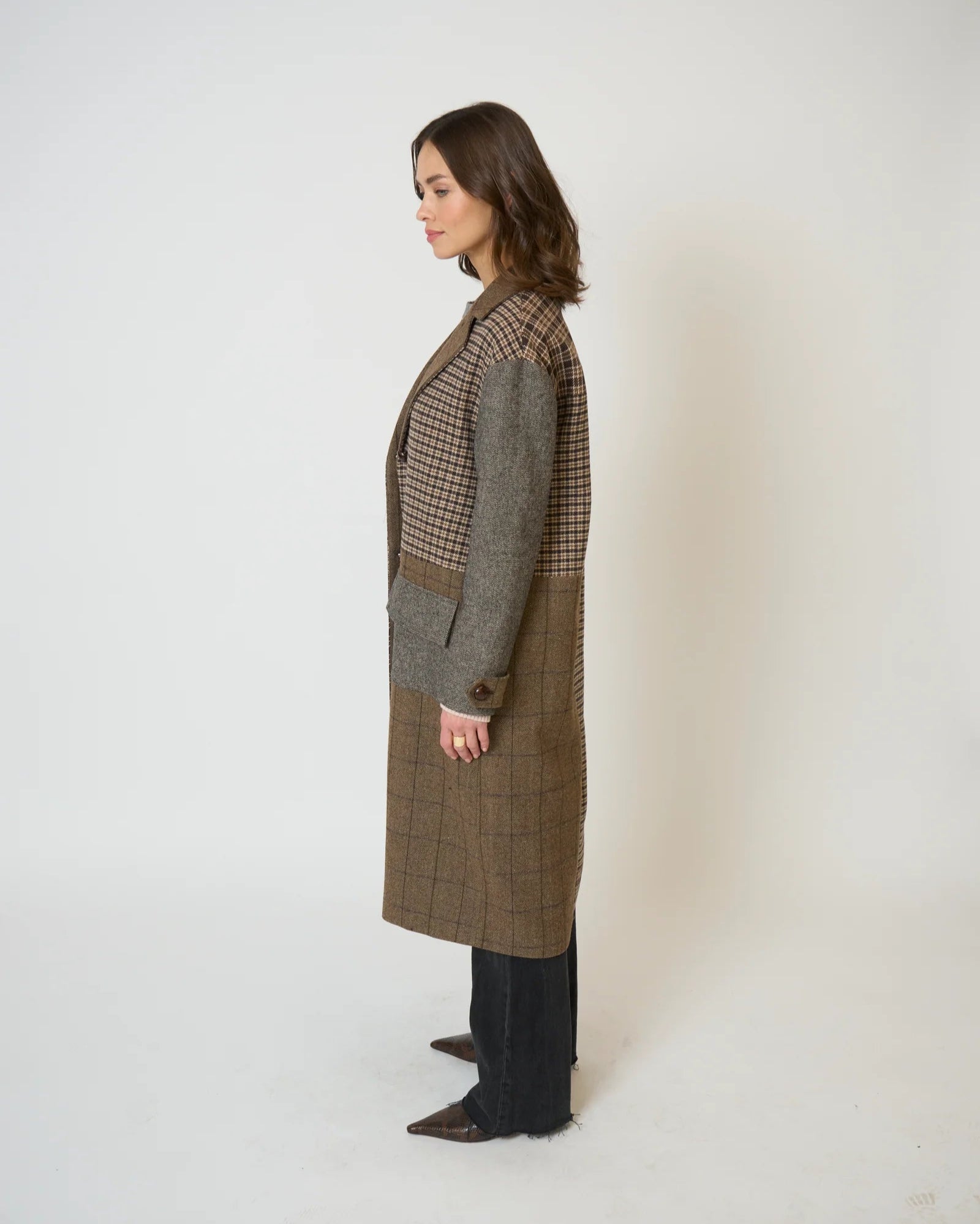 Woman wearing a long brown checkered coat against a white background
