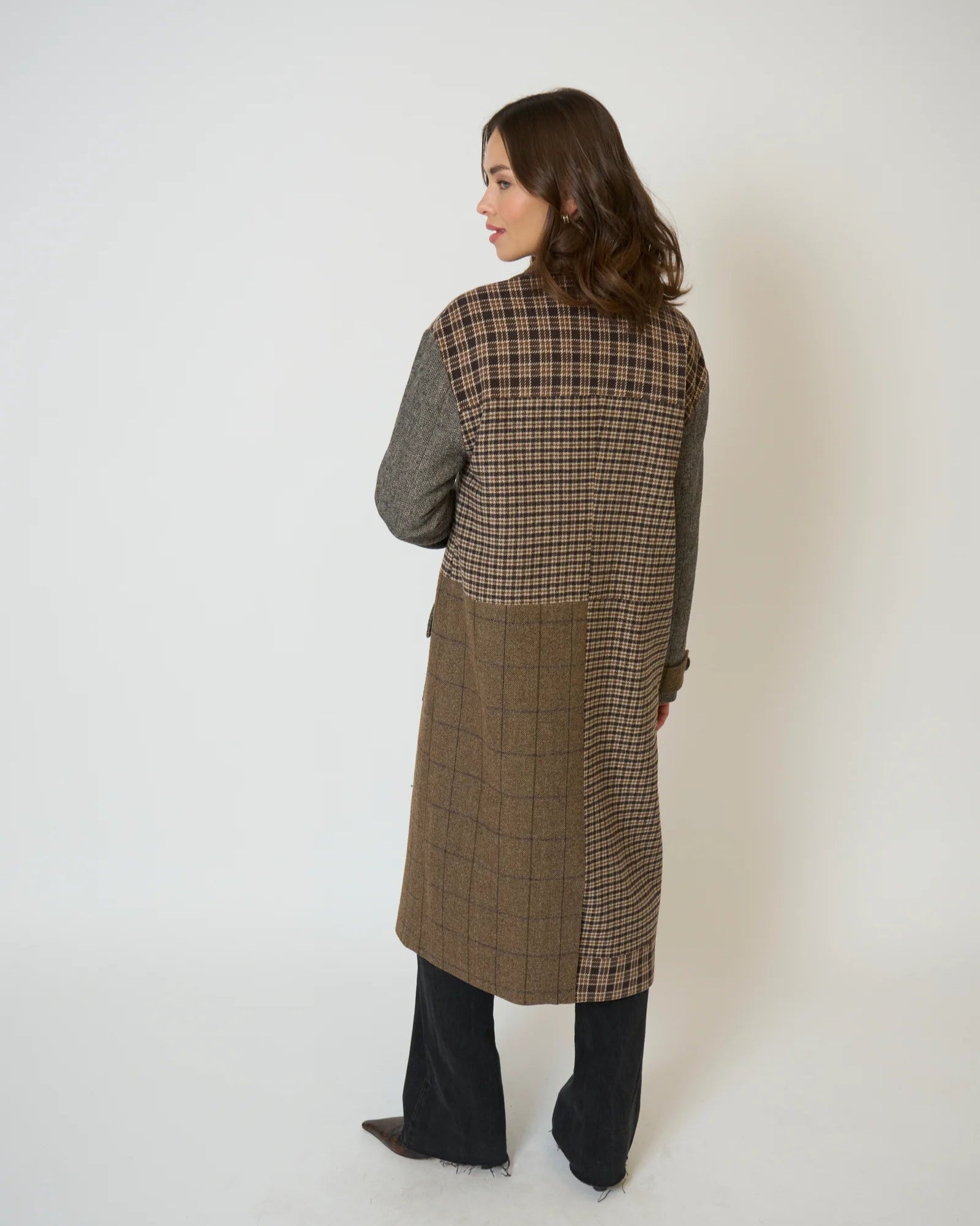 Person wearing a long checkered coat against a white background