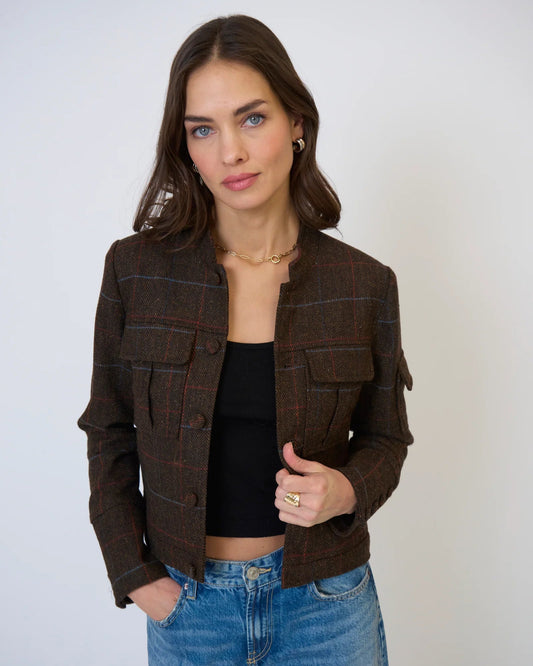 Woman wearing a brown checkered jacket and blue jeans against a white background