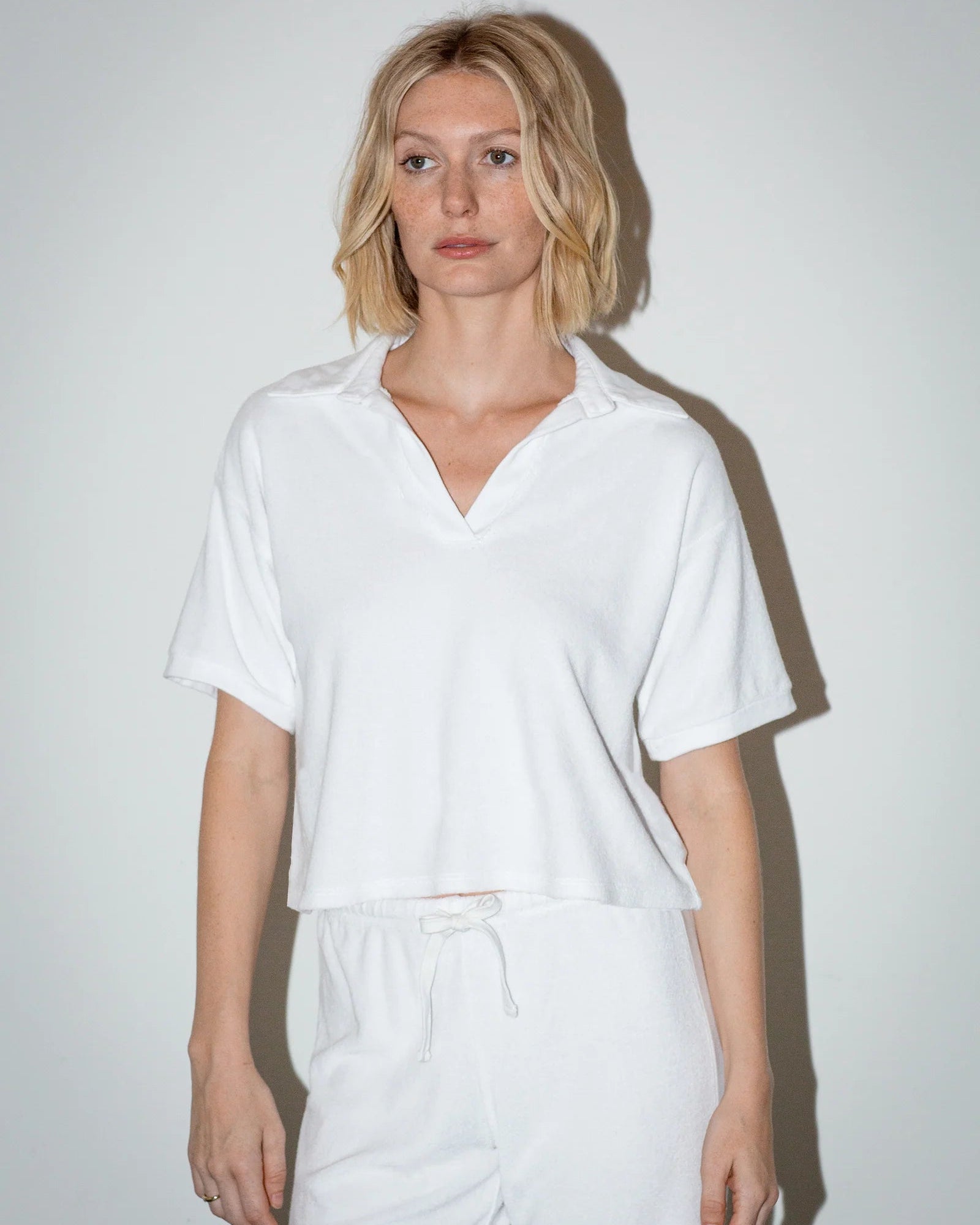 Person wearing a white shirt and pants against a plain background