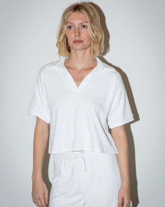Person wearing a white shirt and pants against a plain background