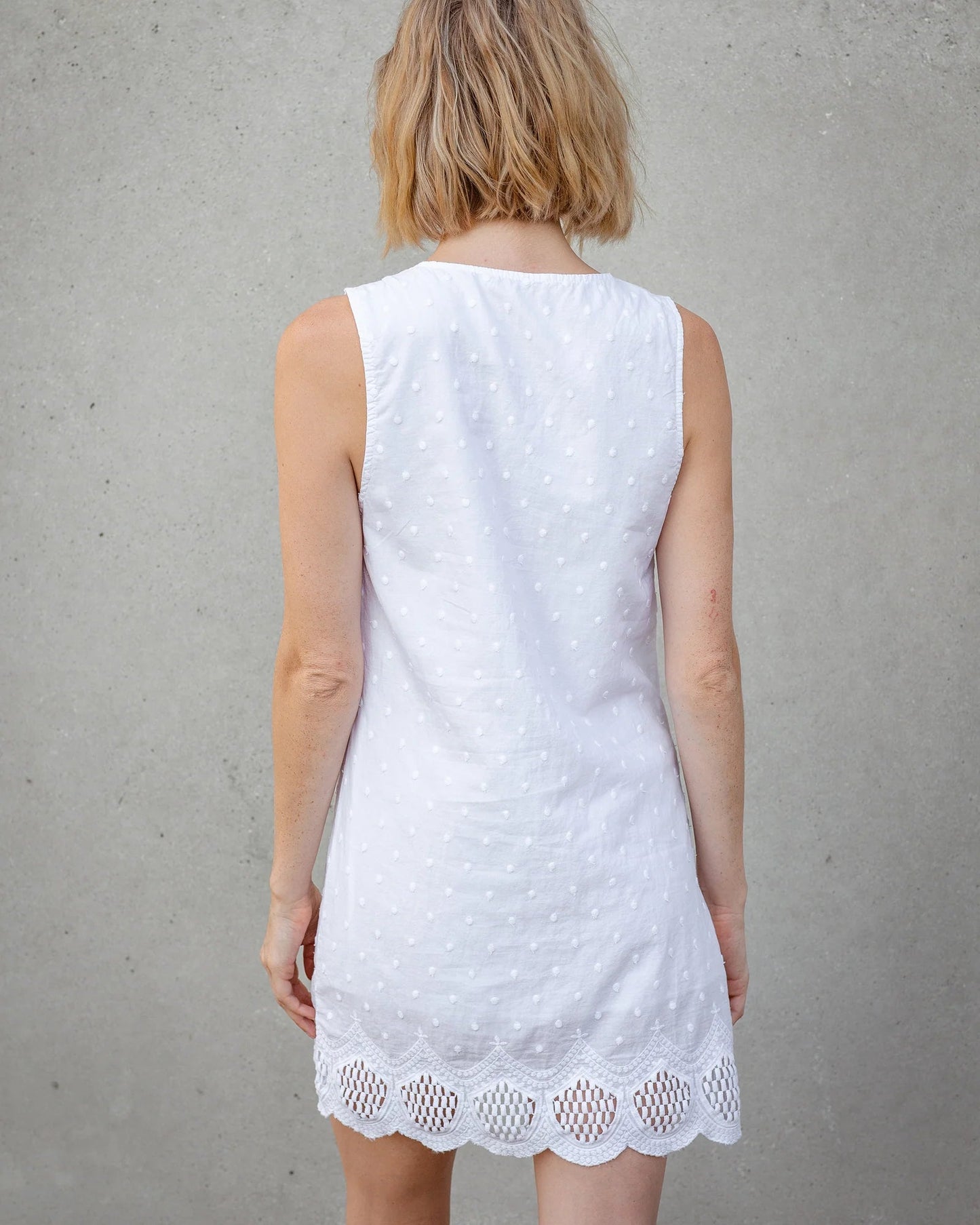 Woman wearing a white lace dress against a gray background