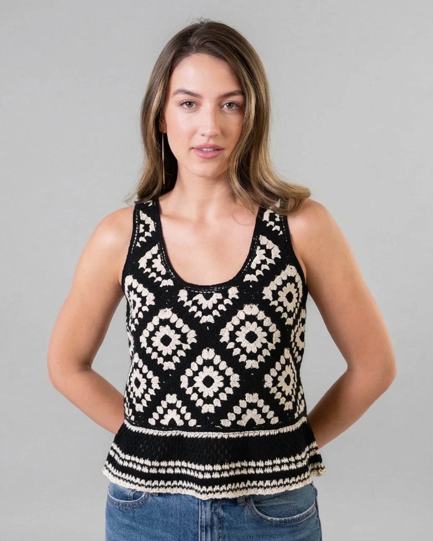 Woman wearing a black and white patterned tank top against a gray background