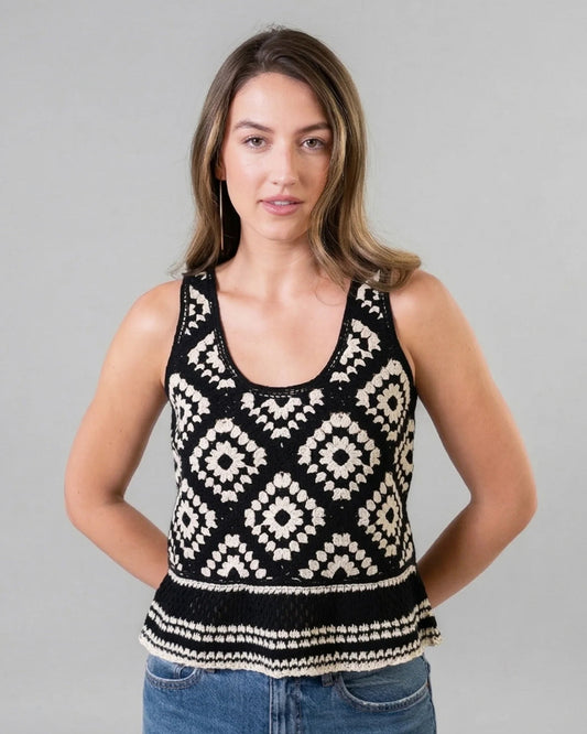 Woman wearing a black and white patterned tank top against a gray background