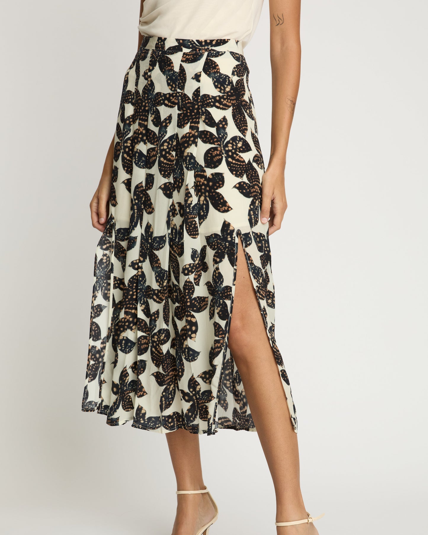 Person wearing a floral patterned skirt with a slit on a white background