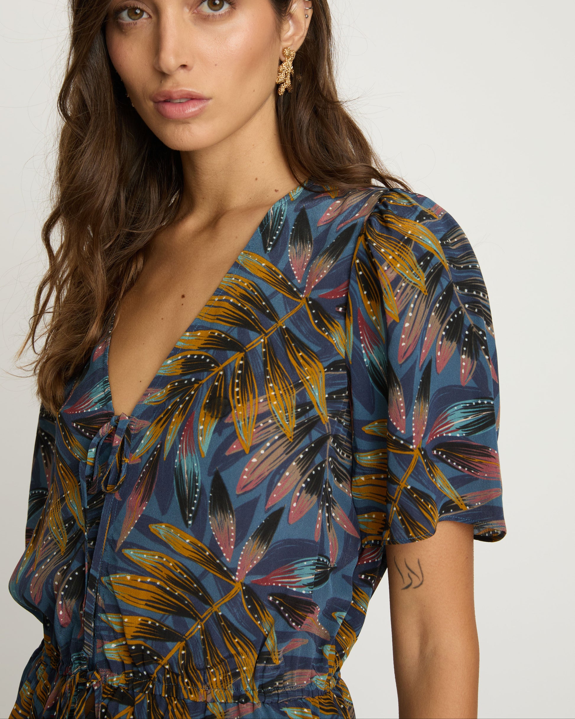 Woman wearing a colorful patterned top against a plain background