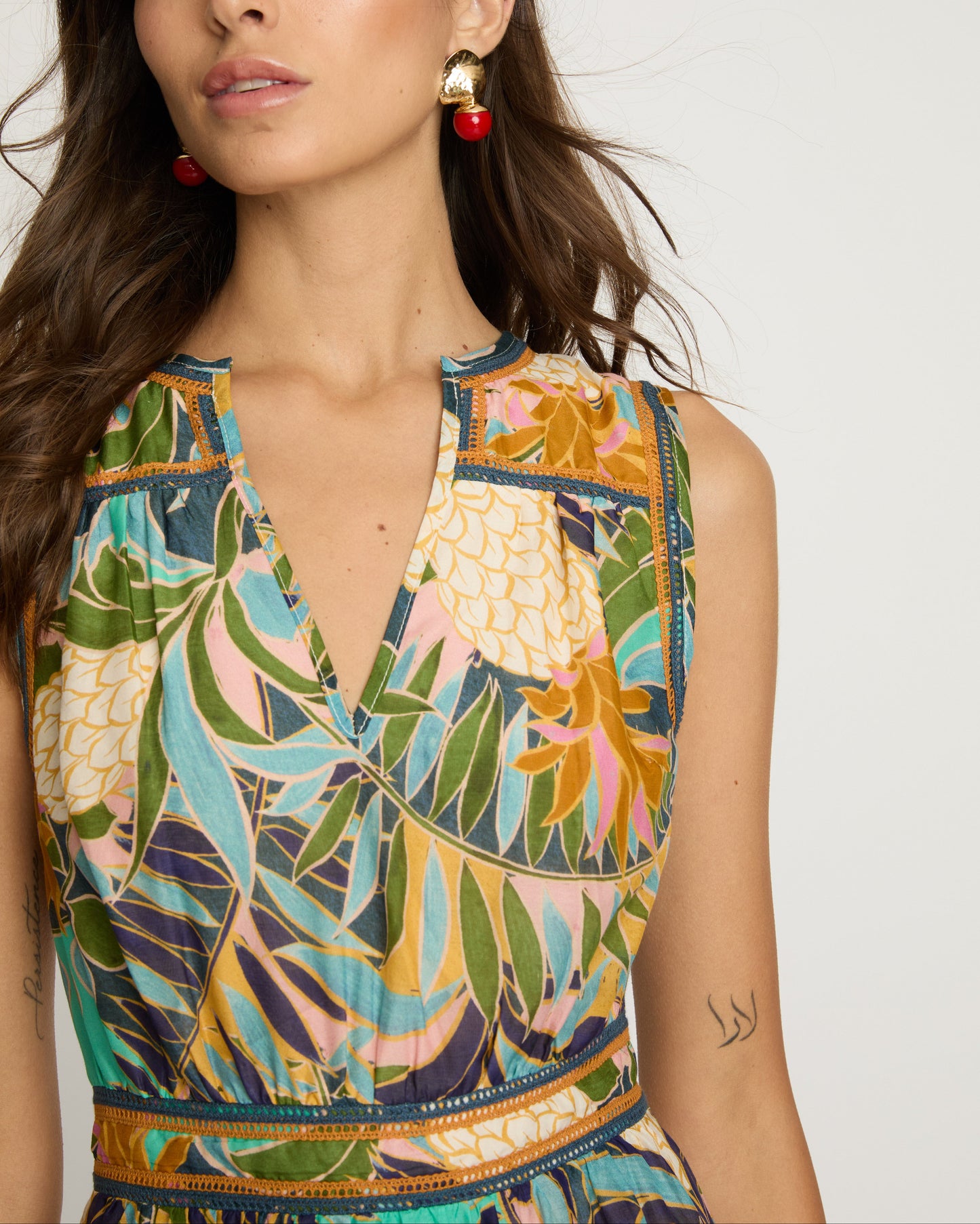 Woman wearing a colorful sleeveless top with a tropical leaf pattern on a white background