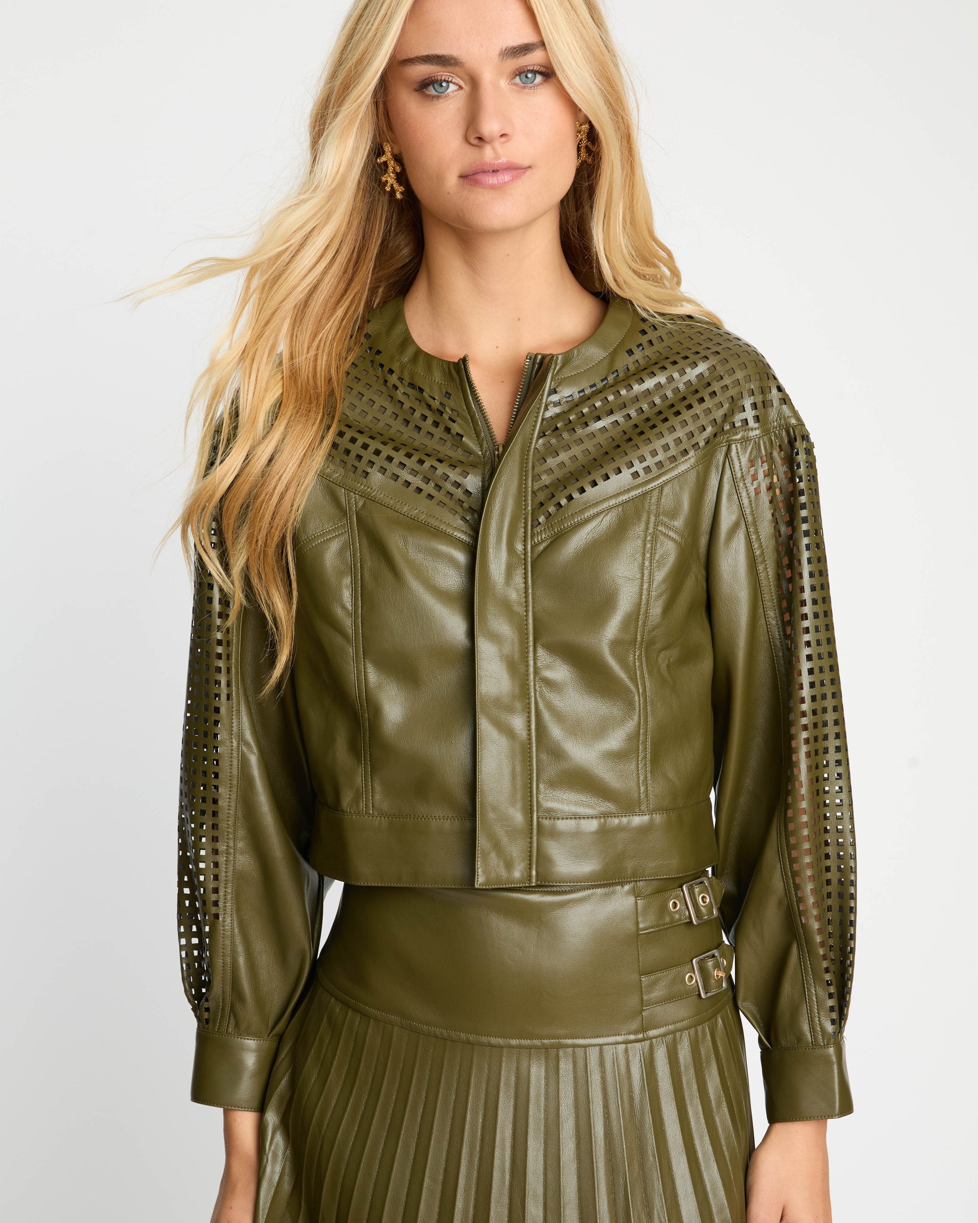 Woman wearing a green leather jacket with decorative cutouts on a white background