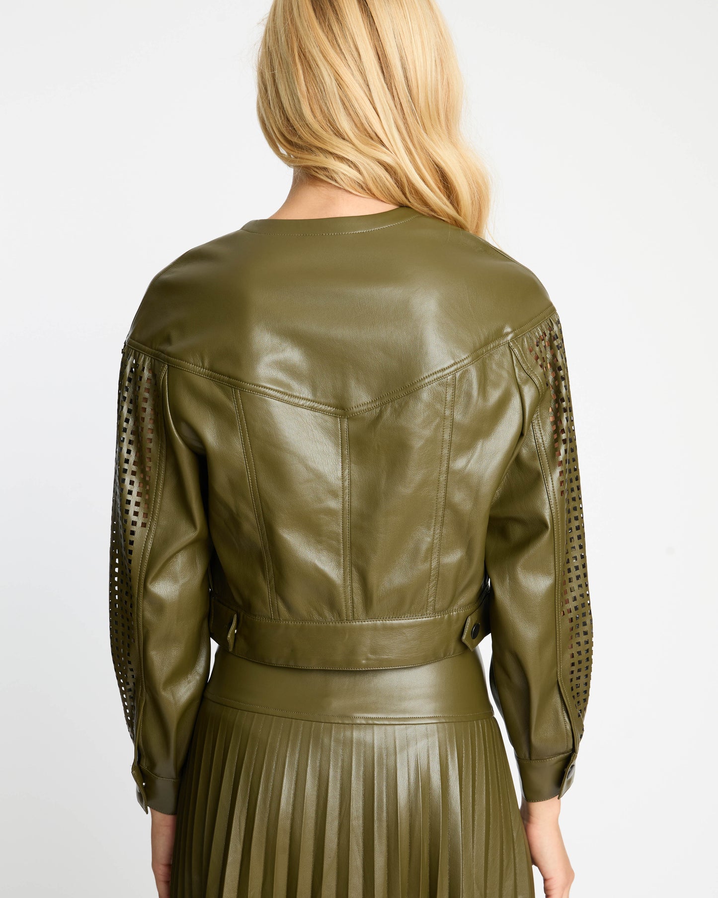 Person wearing an olive green leather jacket with lace sleeves on a white background