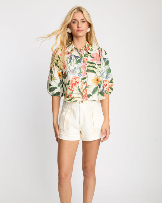 Woman wearing a floral blouse and white shorts on a white background