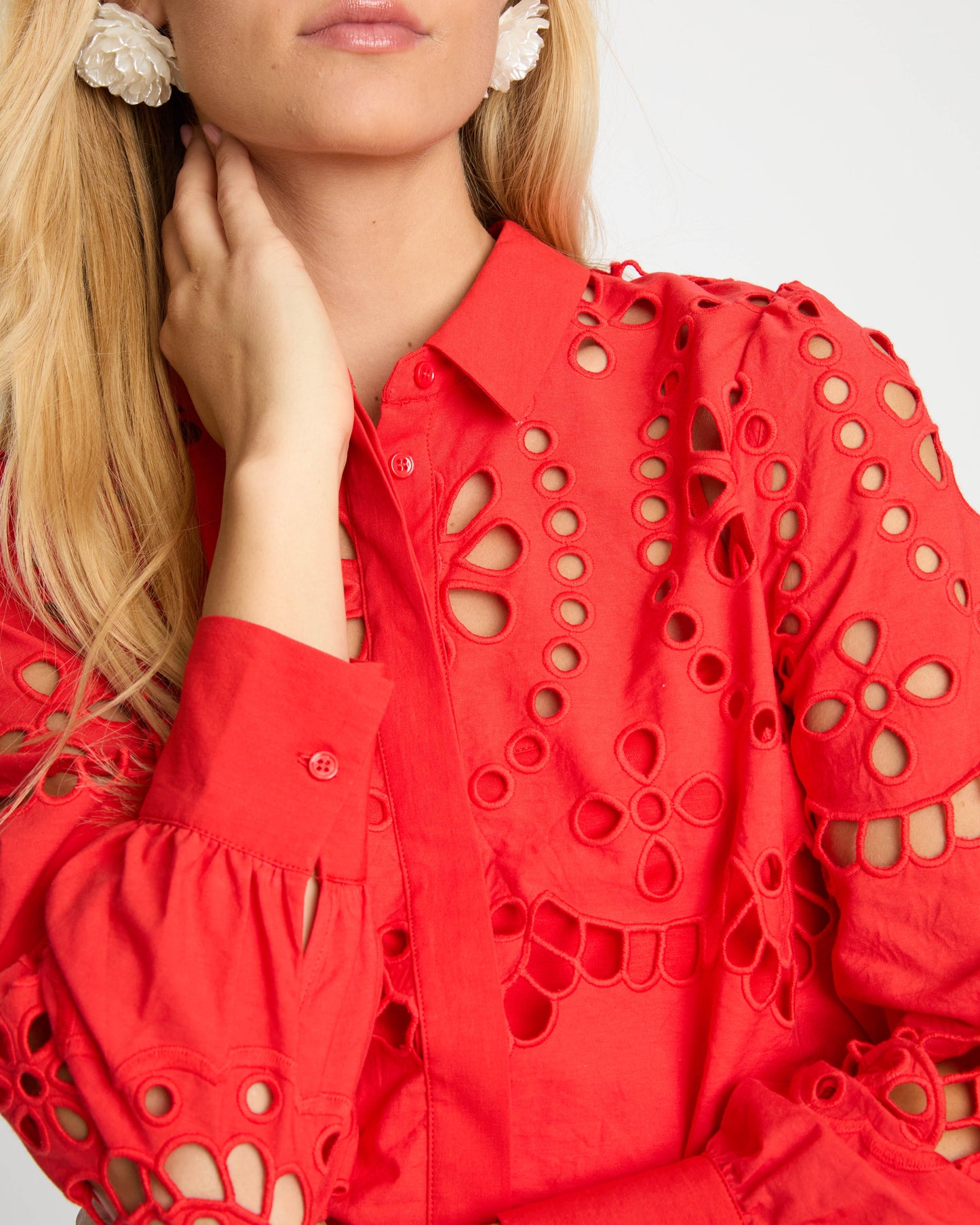 Woman wearing a red blouse with cut-out details on a white background