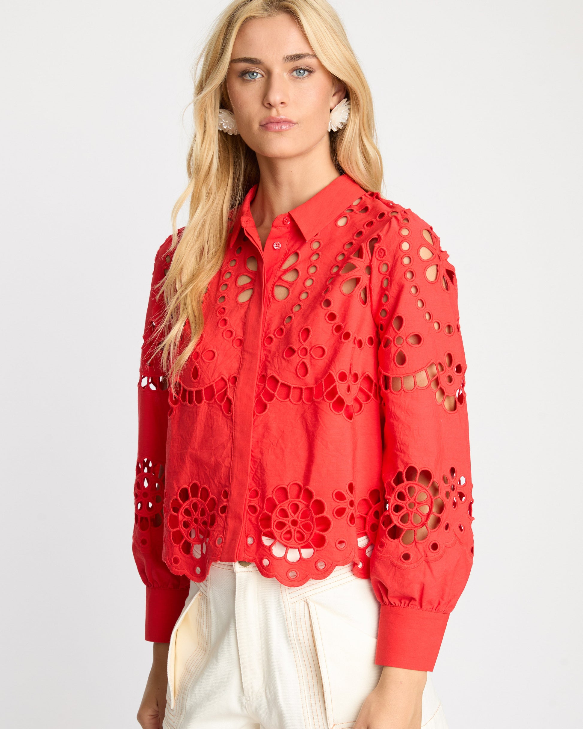 Woman wearing a red lace blouse with a white background