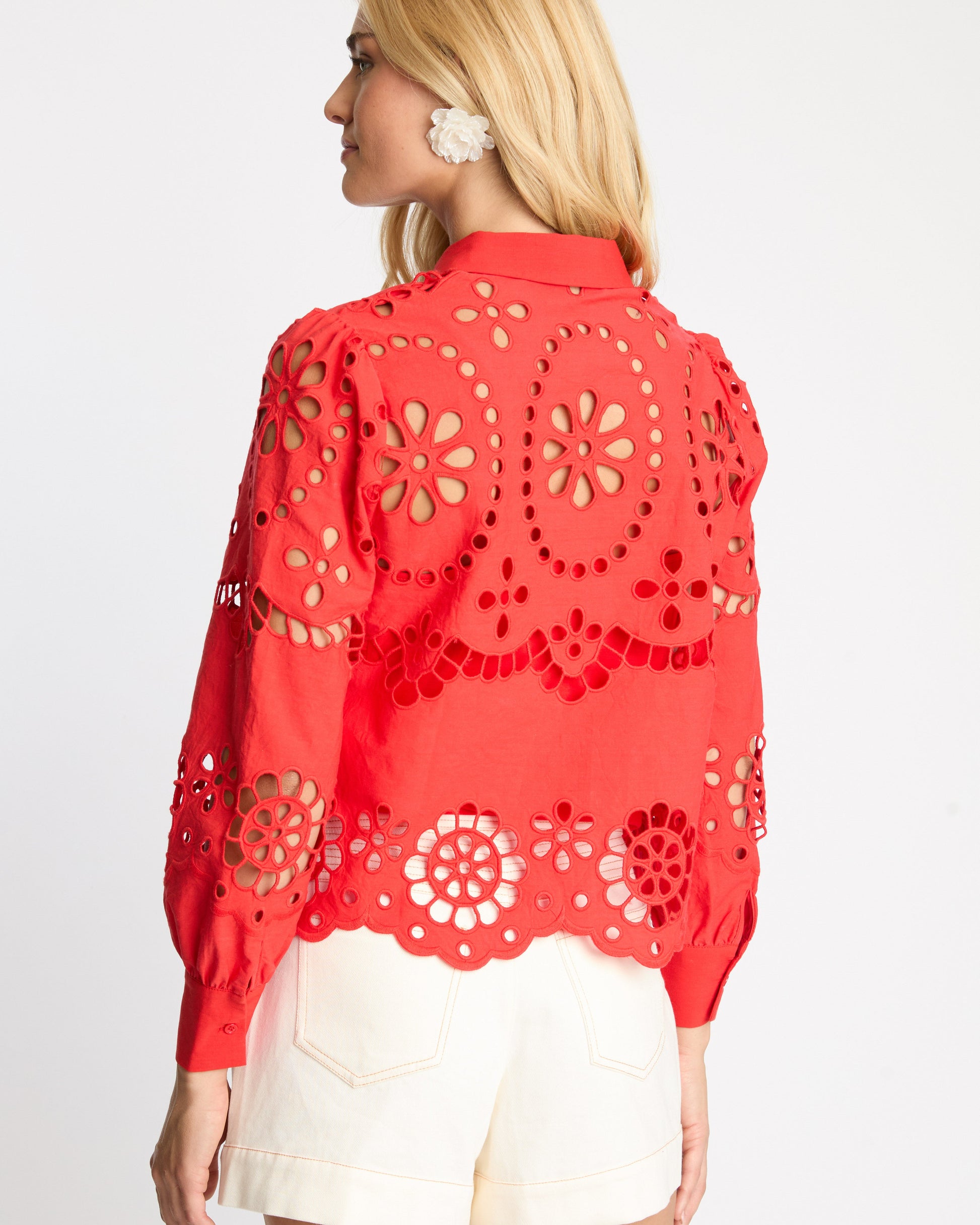 Woman wearing a red lace top with cut-out patterns on a white background