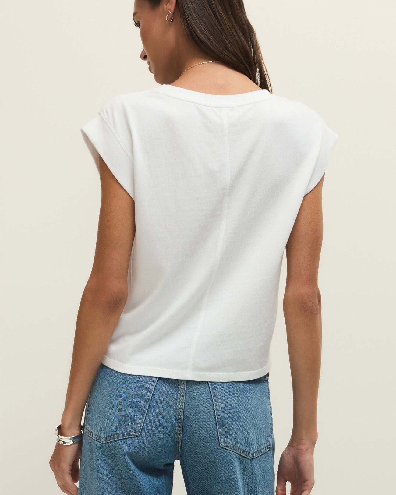 Person wearing a white top and blue jeans on a plain background
