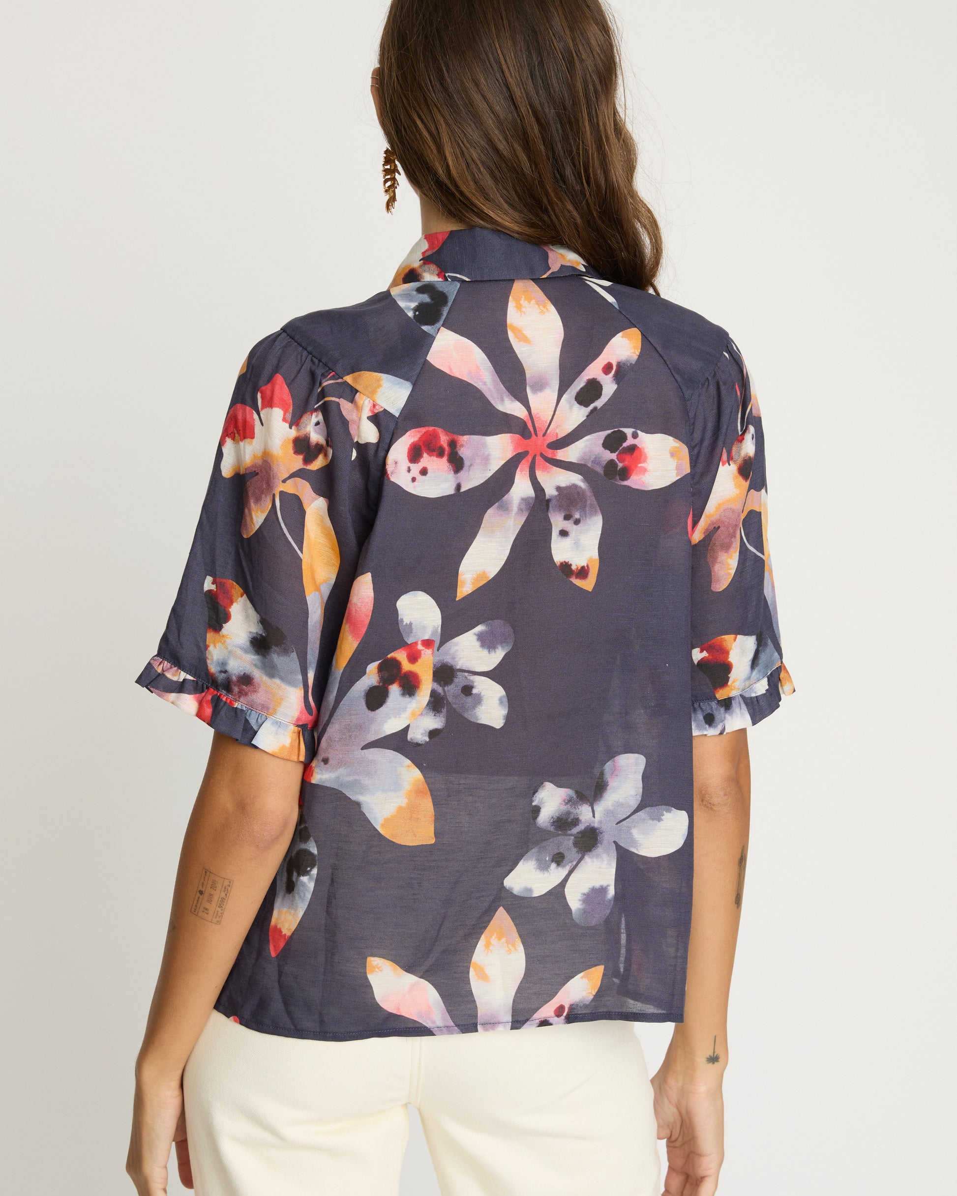Woman wearing a floral patterned shirt with a plain background