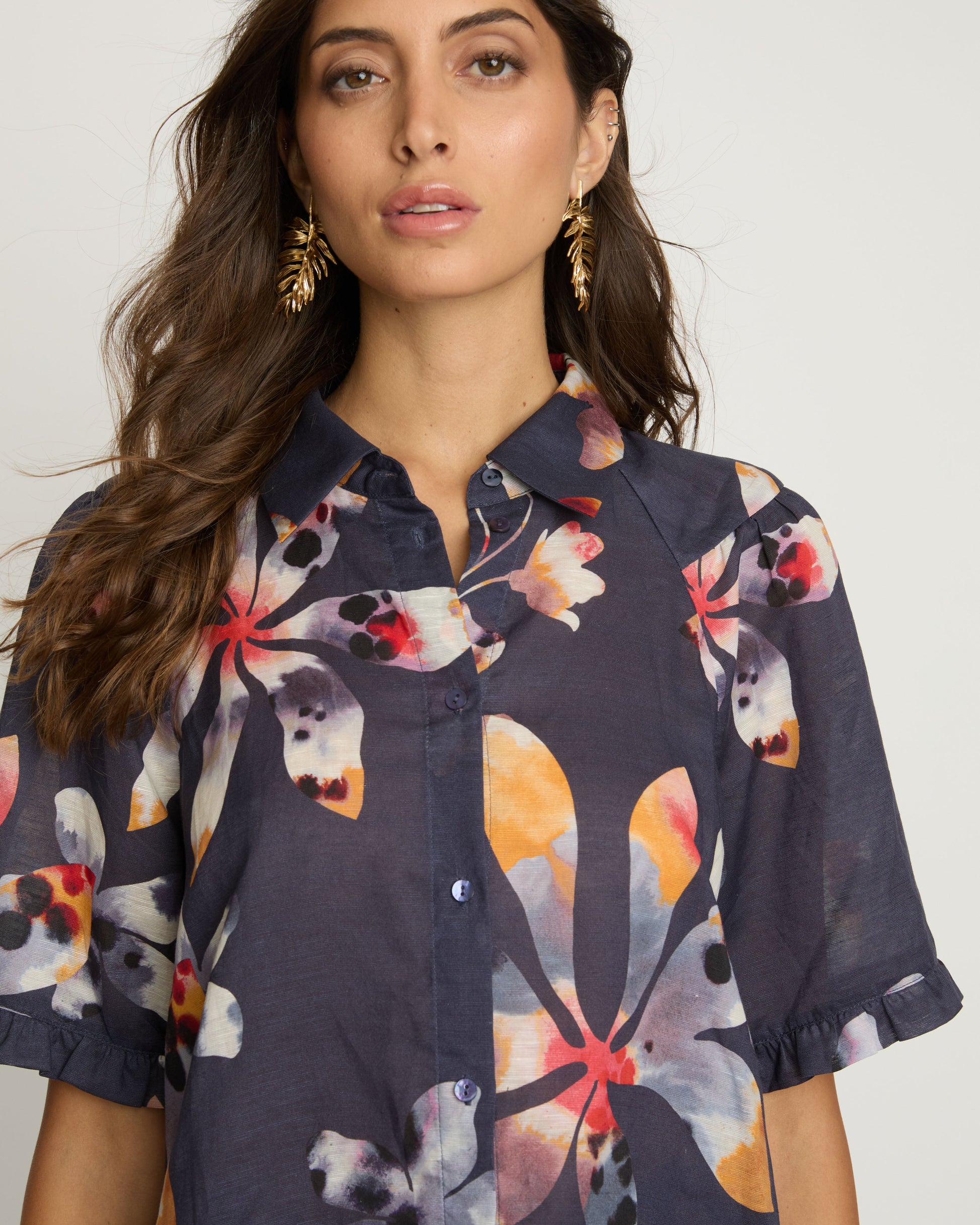 Woman wearing a dark blue floral shirt against a white background