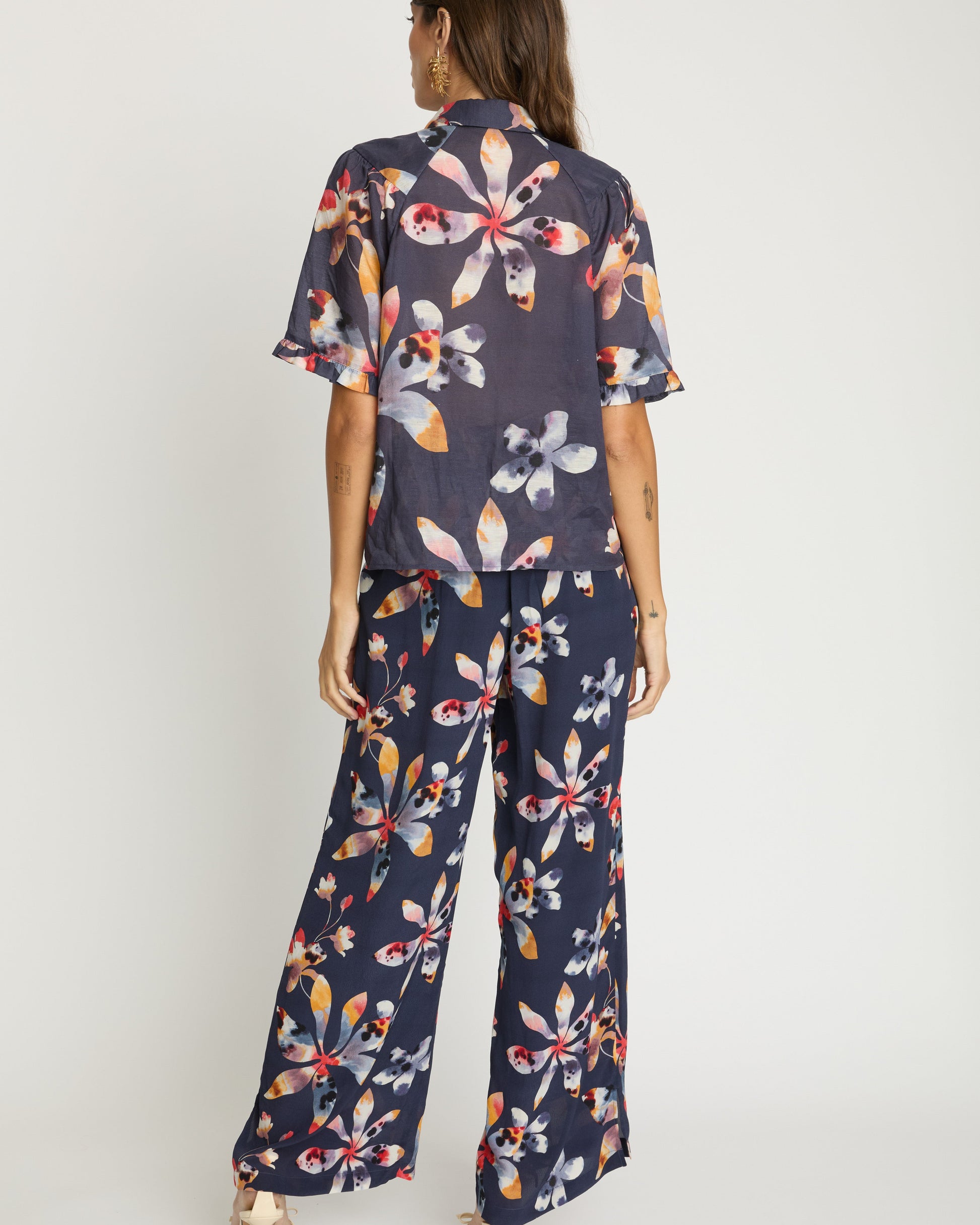 Woman wearing a navy floral jumpsuit on a white background