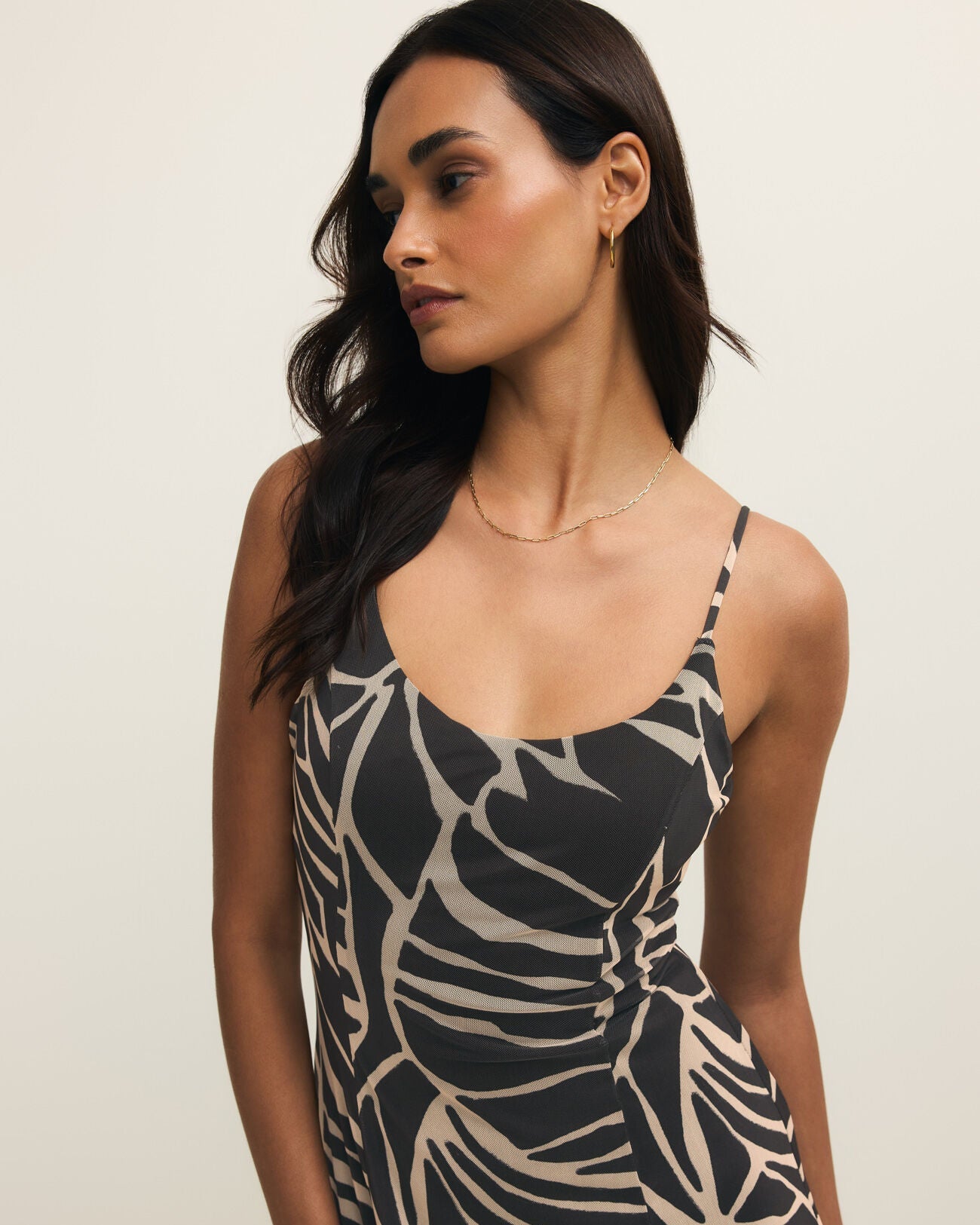 Woman wearing a black and beige patterned dress against a plain background