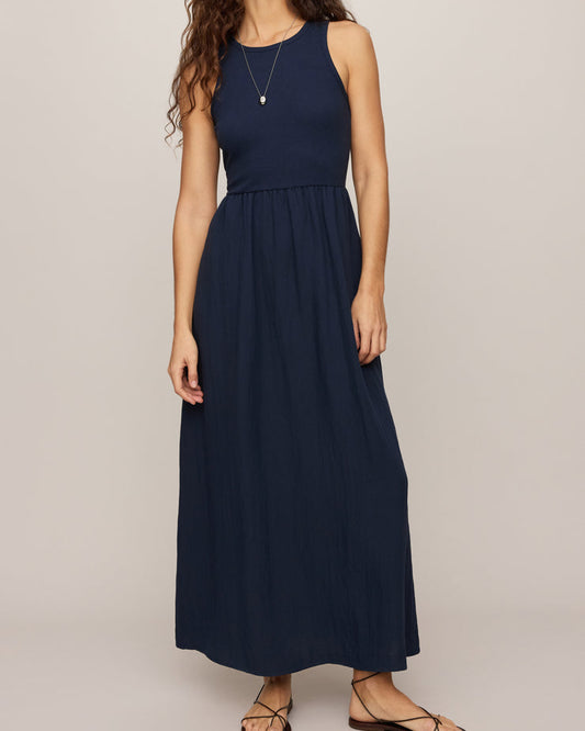 Woman wearing a navy blue sleeveless dress against a plain background