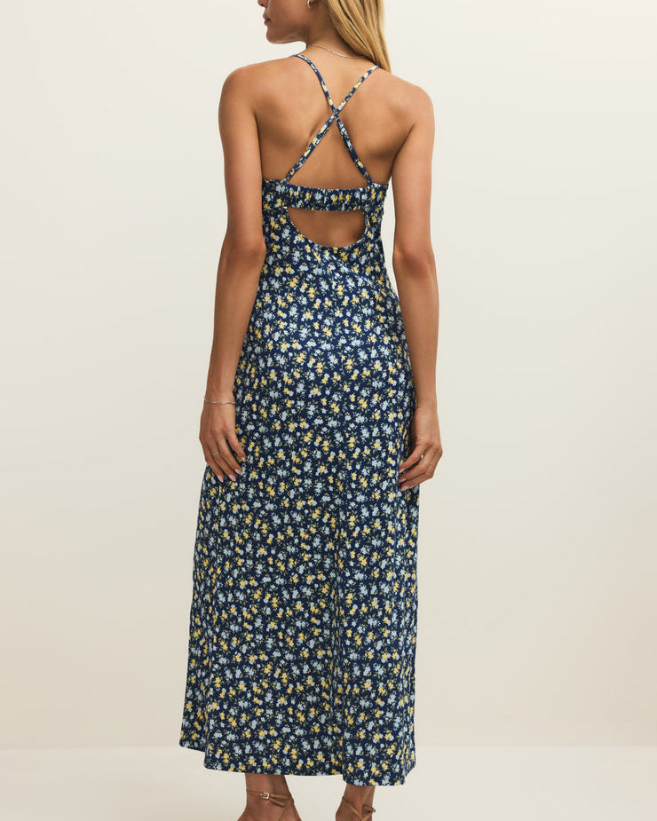 Woman wearing a blue floral dress with thin straps on a beige background