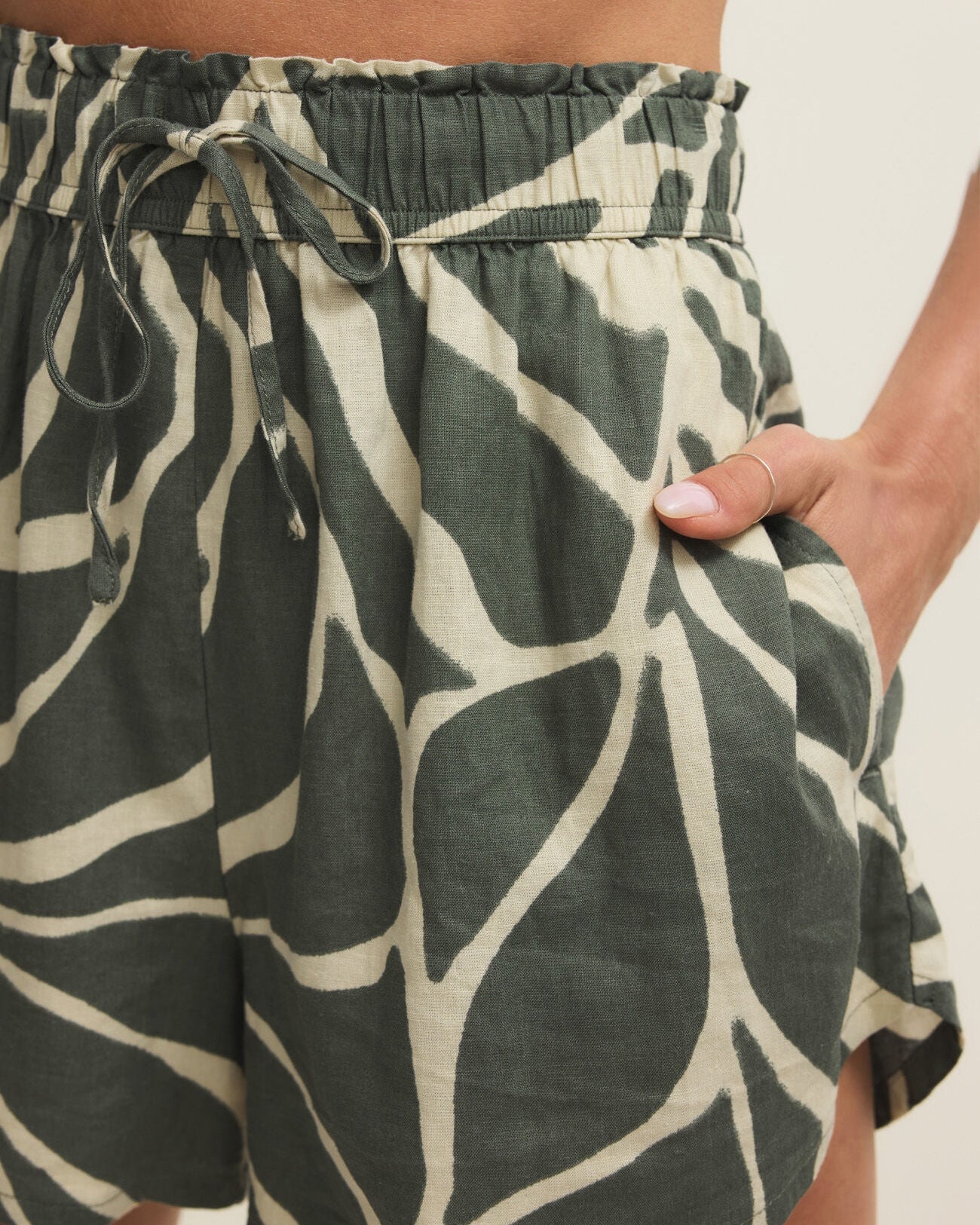 Green and white patterned shorts worn by a person on a neutral background