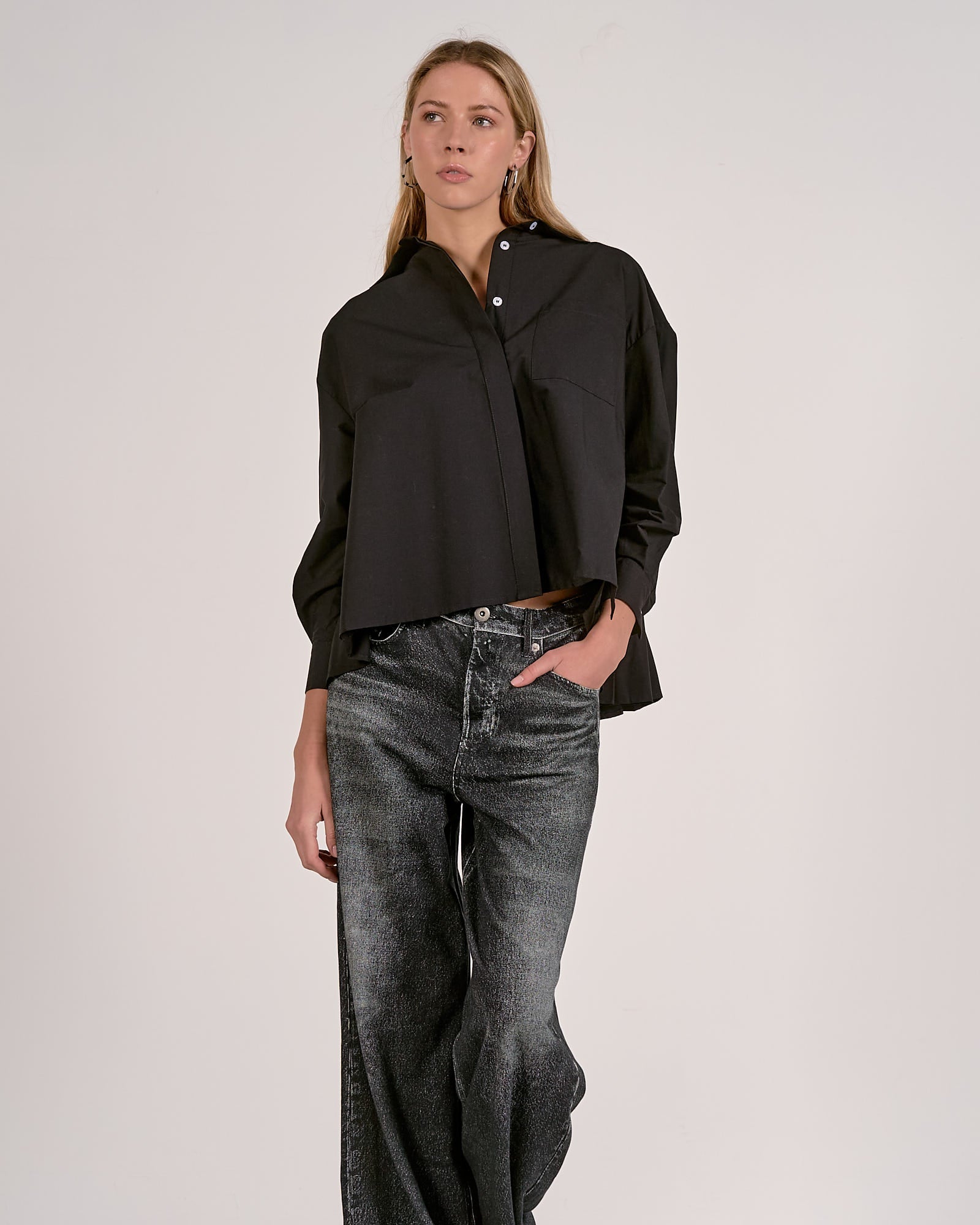 Woman wearing a black shirt and wide-leg jeans against a white background