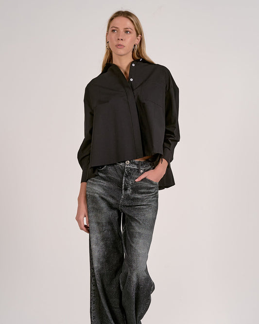 Woman wearing a black shirt and wide-leg jeans against a white background