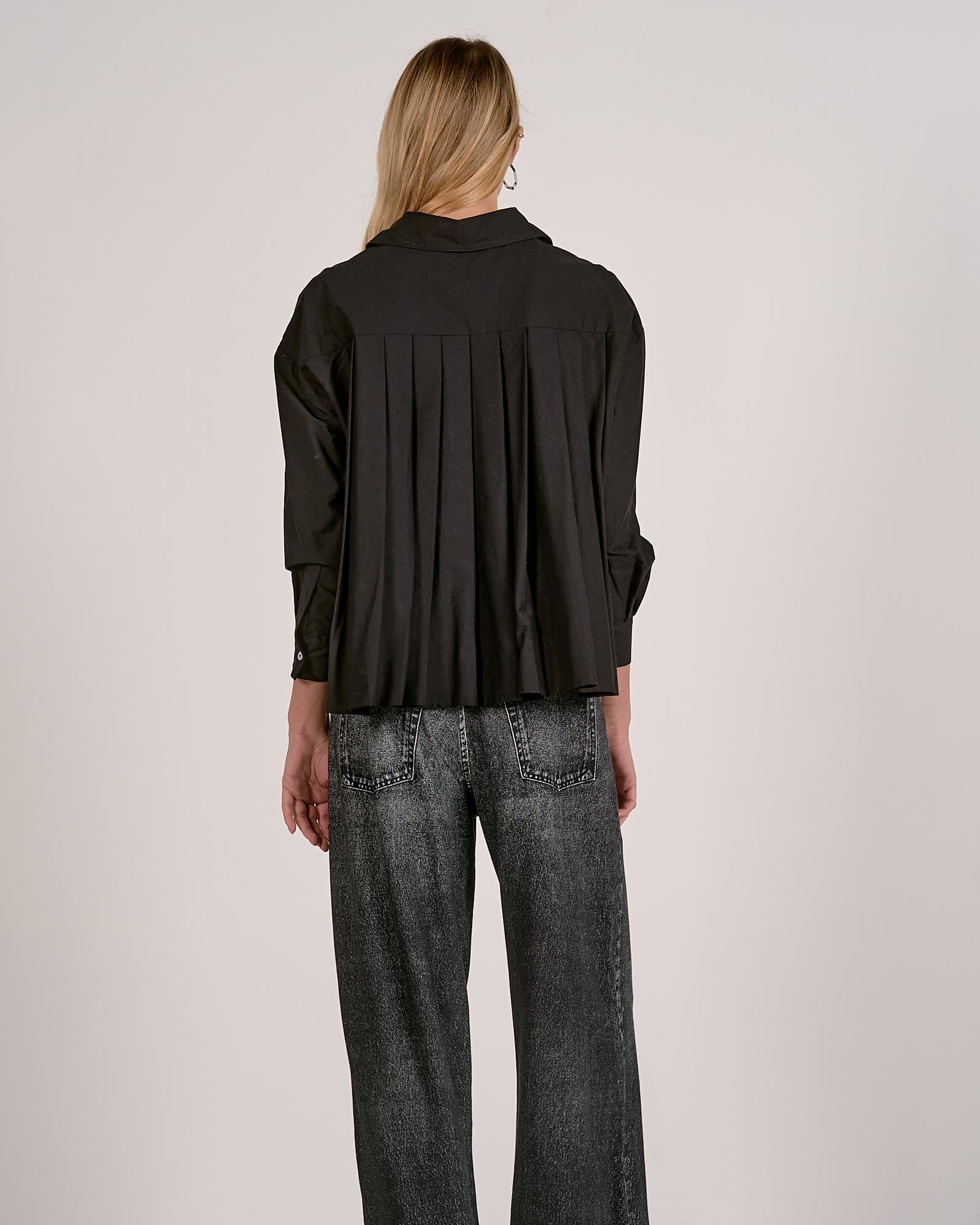 Person wearing a black shirt and dark jeans on a white background