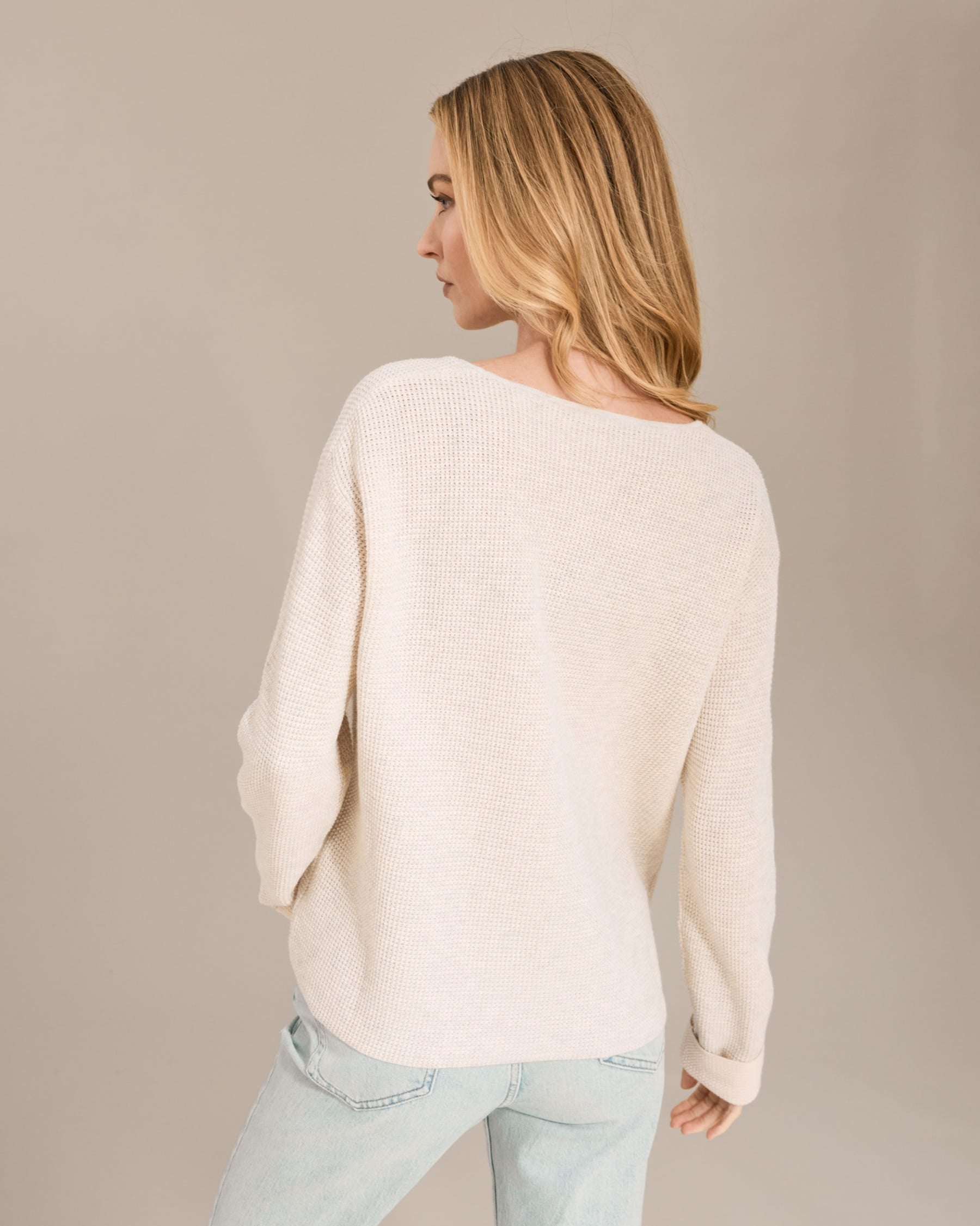 Woman wearing a cream sweater against a beige background