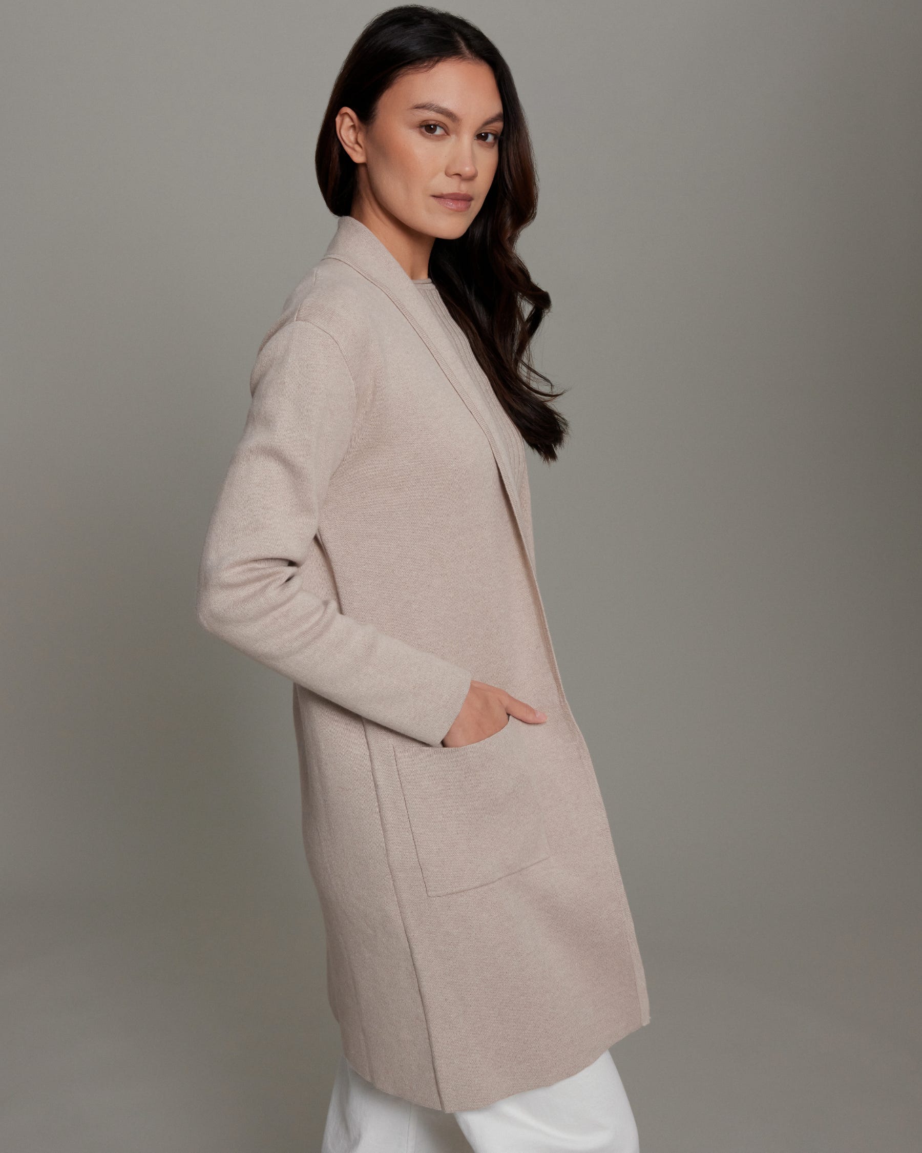 Woman wearing a beige coat against a gray background