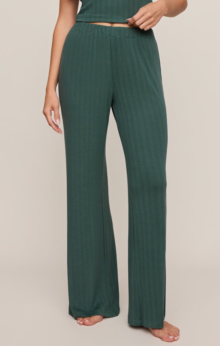 Green ribbed lounge pants worn by a person on a beige background