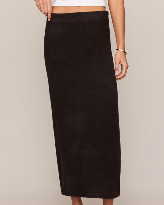 Person wearing a black skirt on a plain background