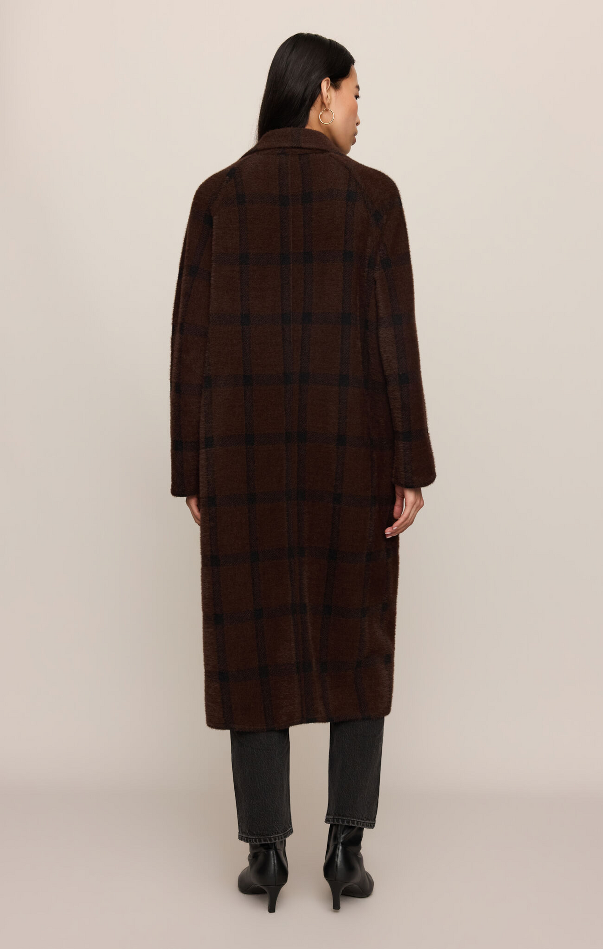 Person wearing a brown checkered coat on a beige background