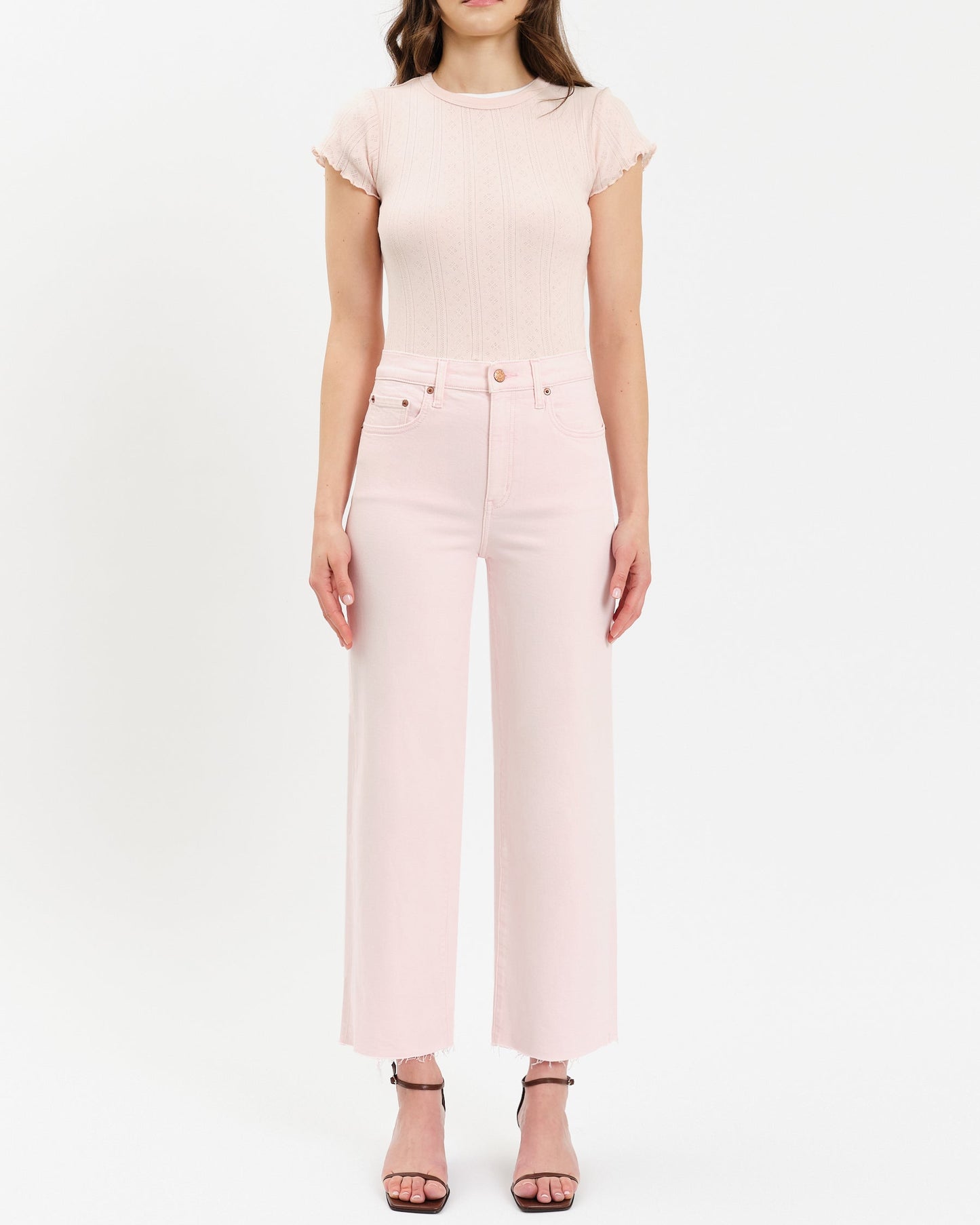 Woman wearing a pink top and pants on a white background
