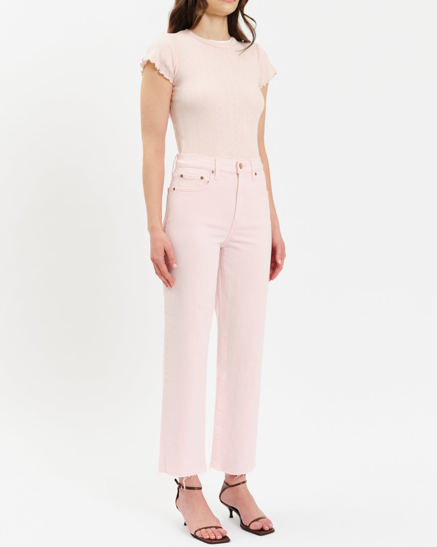 Woman wearing a light pink top and pants on a white background